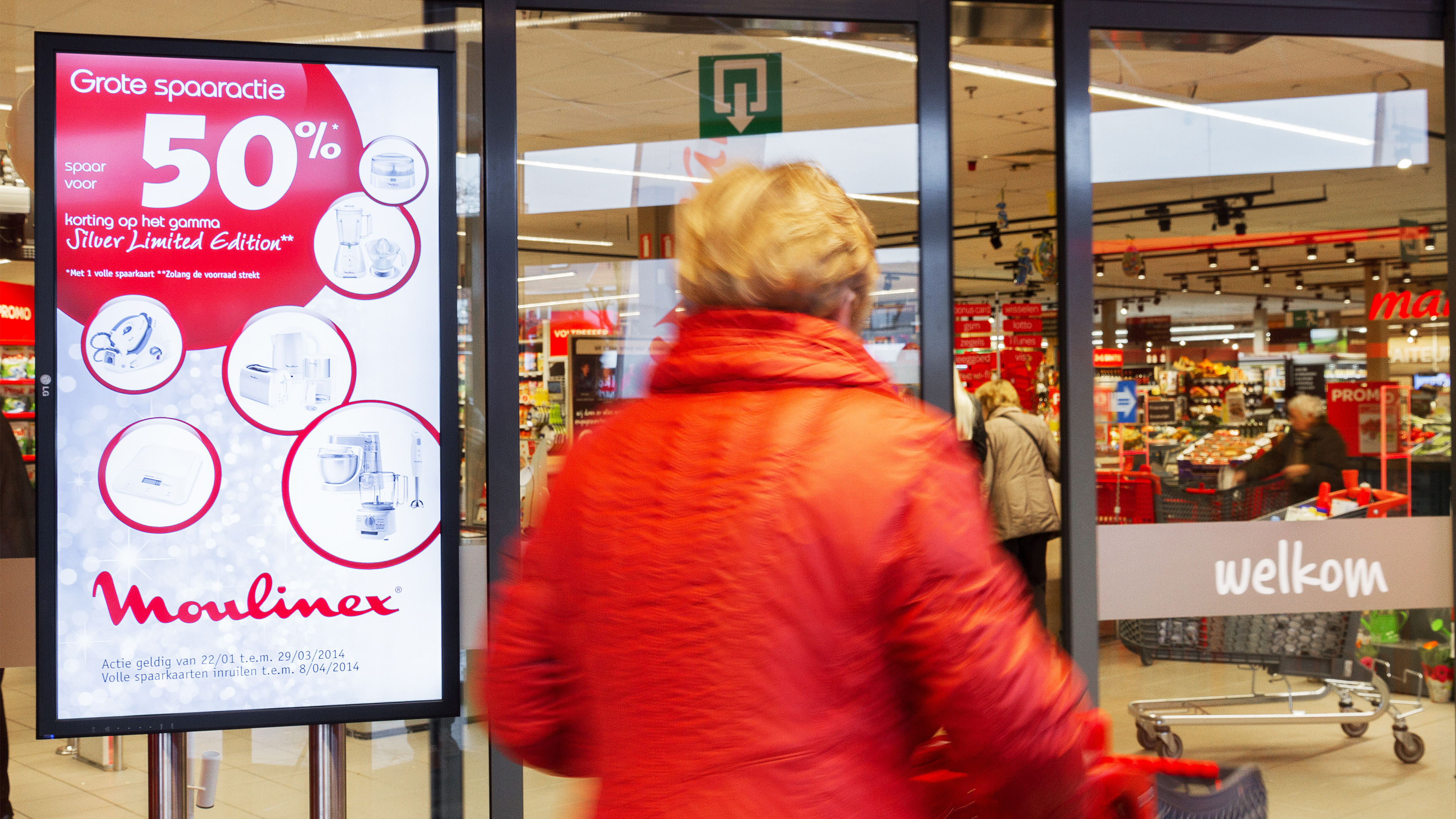 A woman entering a store with a digital screen at the entrance